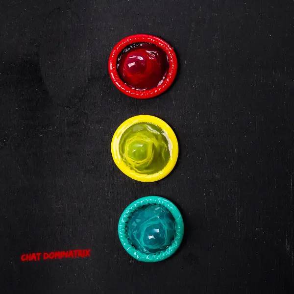 Three colored condoms arranged as a traffic light, red, yellow, and green, symbolizing the traffic light system for safe words and consent in BDSM. Featured in 'Safe Words & Limits: How to Set Boundaries in BDSM' on ChatDominatrix.com