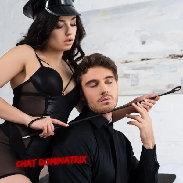 A seductive dominatrix in a sheer black outfit and leather cap uses a riding crop to guide her suited submissive, who surrenders to her control. Transform your dynamic, build a structured, rewarding femdom relationship with proper training techniques