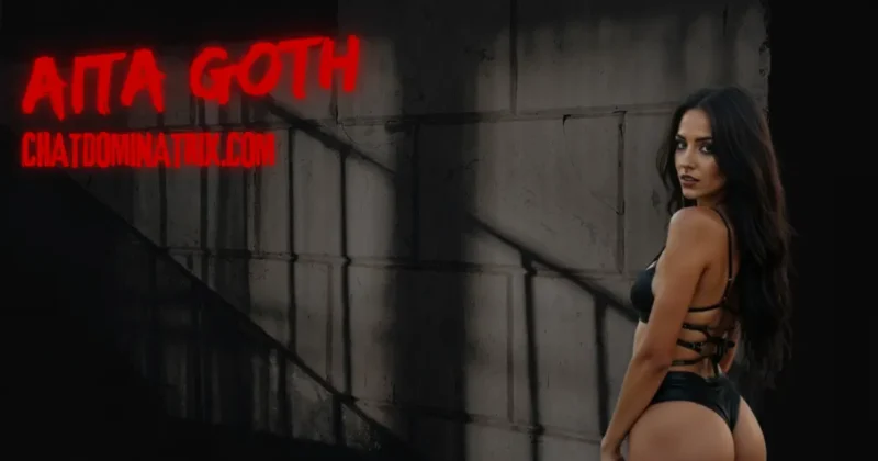 Dark-haired dominatrix in a strappy black latex bodysuit stands confidently against a shadowed concrete wall, her gaze dominant and inviting. The bold red text "Aita Goth" and "ChatDominatrix.com" reinforces the authoritative presence of the author. This visual sets the tone for a seductive and intense exploration of spanking and impact play in femdom, where psychological power meets physical expression.
