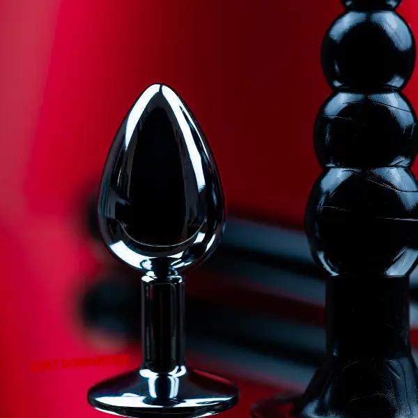 Luxury metal and silicone butt plugs displayed on red velvet – the ultimate guide to using butt plugs in BDSM by Aita Goth on ChatDominatrix.com