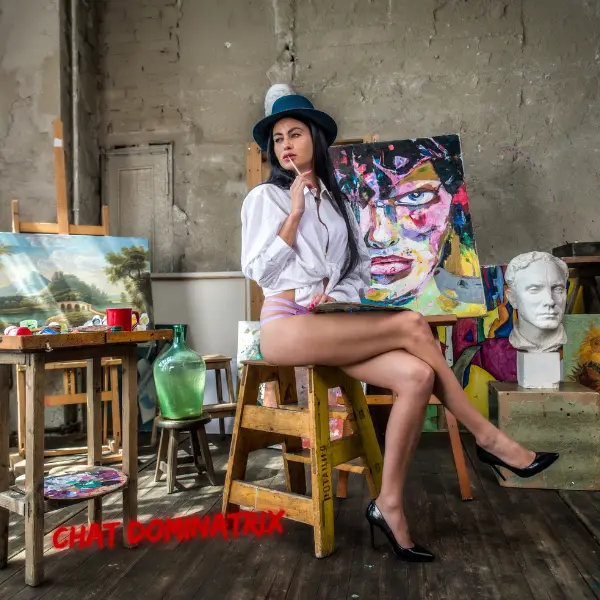 A confident woman in a sensual artist’s studio, dressed in a revealing white shirt and heels, commanding attention with an air of creative dominance. Short Femdom Stories by Aita Goth on Chat Dominatrix