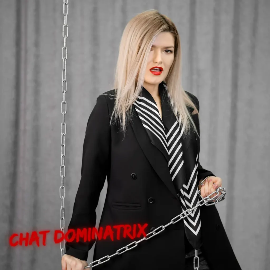 Powerful female Dominant in black blazer gripping chain, portraying elegant keyholder role in male chastity submission dynamic